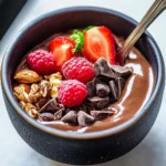 Delicious bowl of chocolate protein pudding topped with fresh berries.