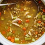 Bowl of high-protein chicken lentil soup with vegetables and shredded chicken